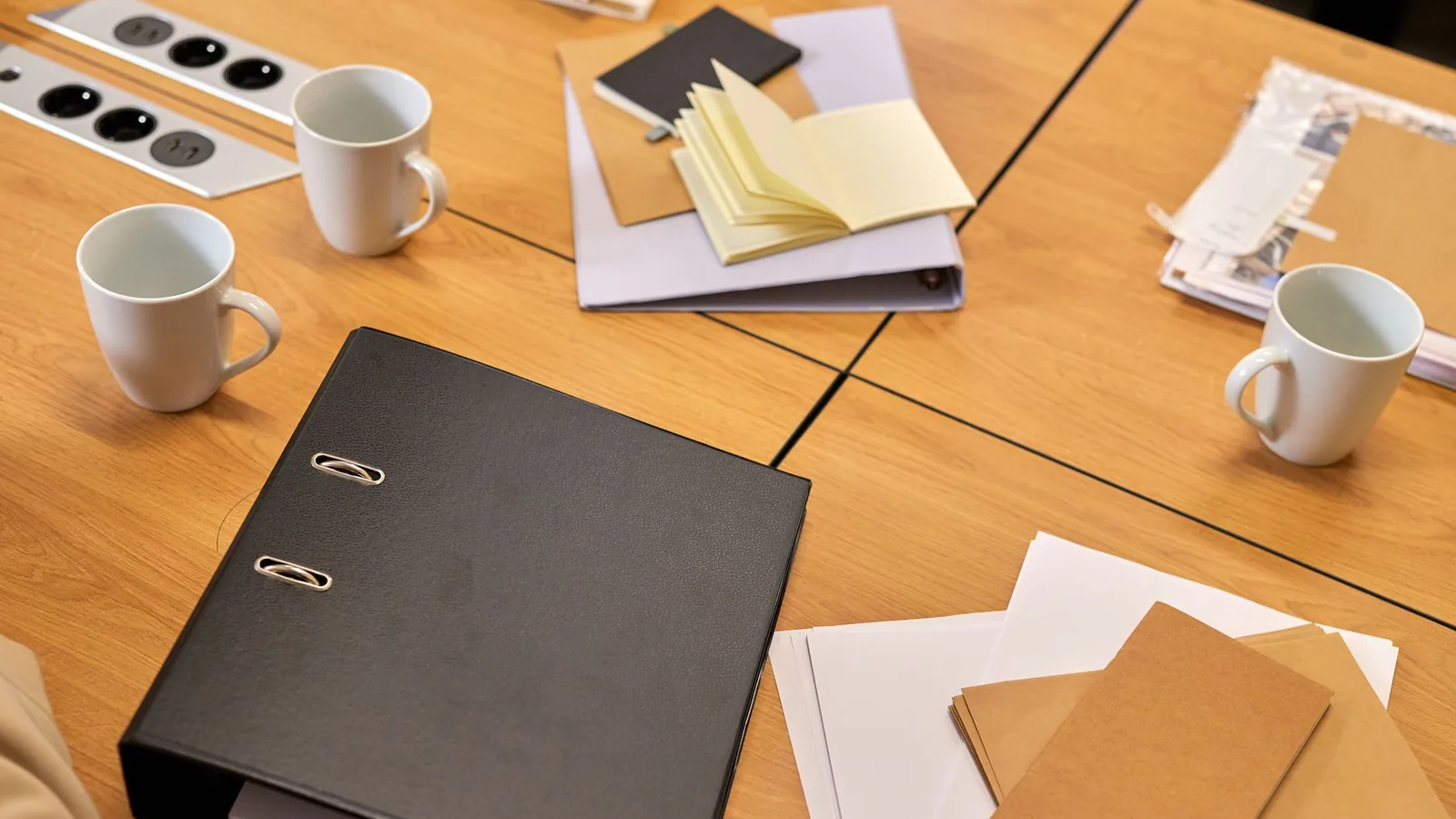 A neat office desk with binders, papers, and coffee mugs arranged neatly, offering a professional workspace vibe